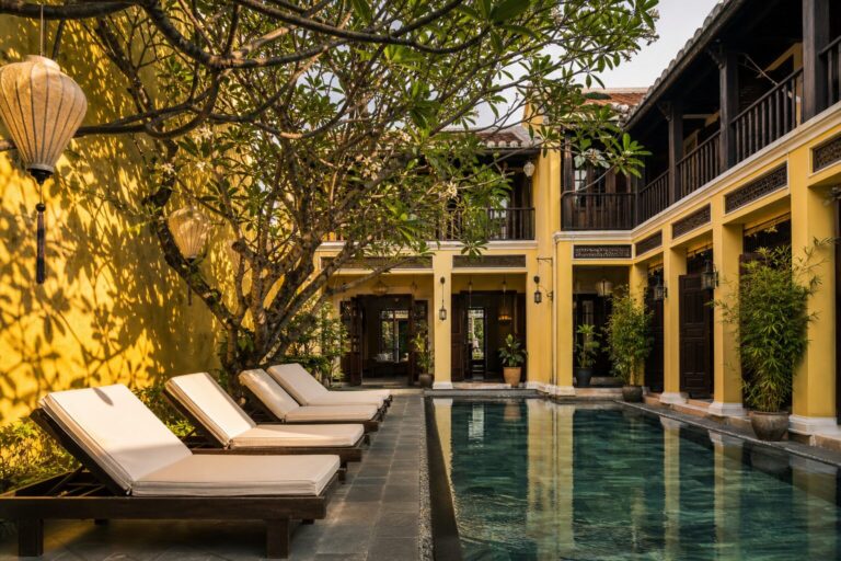 Courtyard and lap pool of a restored heritage boutique hotel in Hoi An with yellow walls and silk lanterns
